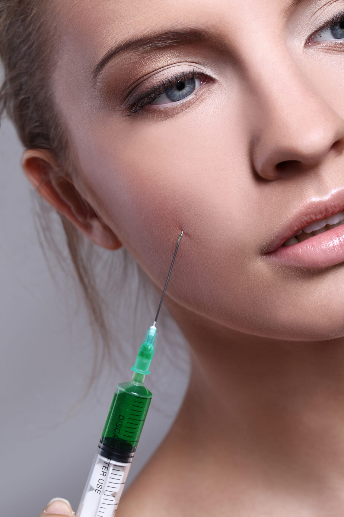 Close-up of a woman receiving an injectable treatment on her cheek.